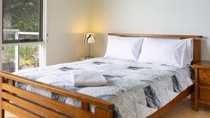 A bedroom with a wooden bed frame, a quilted bedspread, and a bedside lamp.