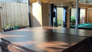 A hot tub in a covered outdoor area with a wooden fence and potted plants. - Beautiful 2BR 2BA Home with Private Pool & Jacuzzi - Includes Pool Table (Sarasota)