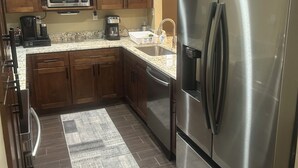 A modern kitchen with wooden cabinets, stainless steel appliances, a microwave, coffee maker, and a refrigerator. - Beautiful 2BR 2BA Home with Private Pool & Jacuzzi - Includes Pool Table (Sarasota)