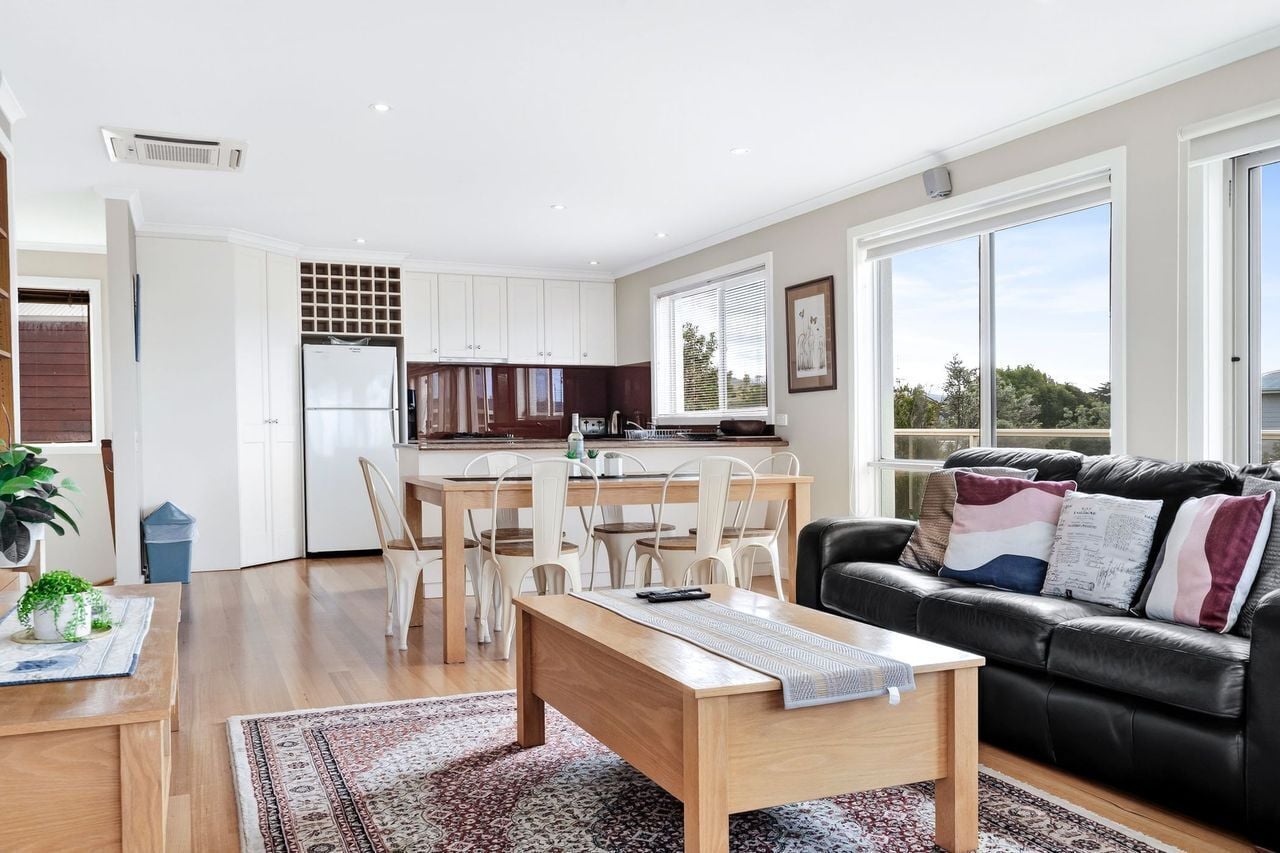 A modern living space with a dining area, kitchen, and seating area.