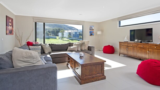 A modern living room with a grey sofa, a wooden coffee table, and a red bean bag.