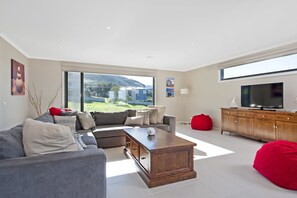 A modern living room with a grey sofa, a wooden coffee table, and a red bean bag.