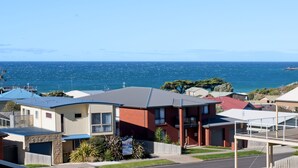 A residential area with houses, a clear view of the ocean, and a distant landmass.