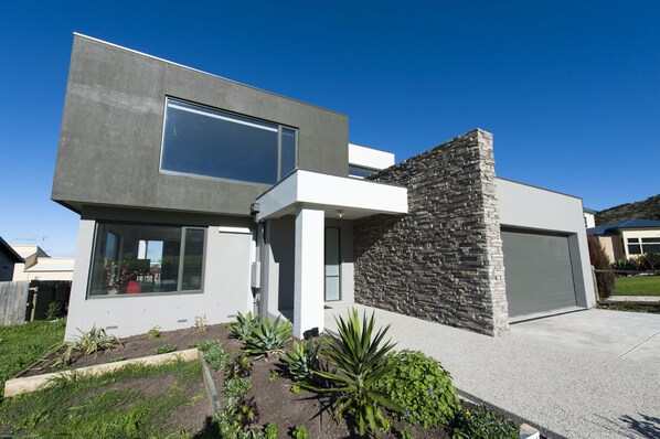 A modern two-story house with a garage, a stone accent wall, and a well-maintained garden.