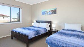 A hotel room with two beds, a large window, and a painting on the wall.