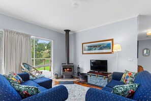 A living room with a fireplace, a television, and a large window.
