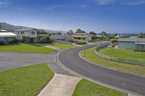 A residential street with houses, a curved road, and a clear view of the ocean. - Barrabay (Apollo Bay)