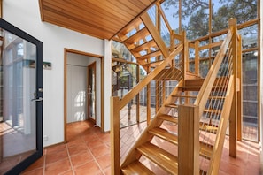 Ein modernes Interieur mit einer Holztreppe, Glastüren und einem Fliesenboden.