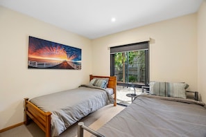 Ein Schlafzimmer mit zwei Einzelbetten, einem großen Fenster und einem Sonnenuntergangsbild.