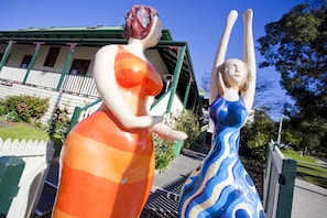 Two outdoor statues of women in colorful dresses.