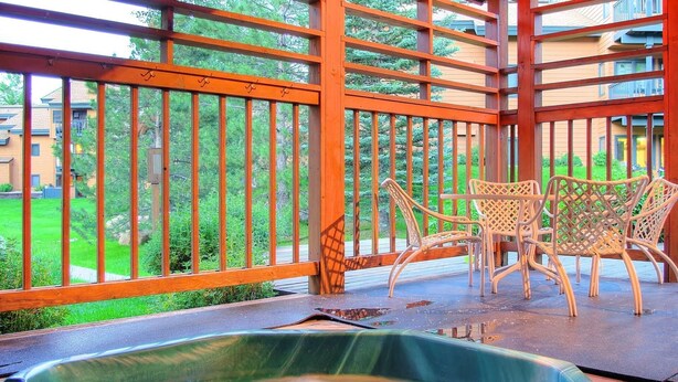 A hot tub on a wooden deck with a view of a garden and buildings. - Great Value! Epic Slope Views-Hot Tub+ Steps to Eat/Drink/Shops/Free Bus-W/D in Unit-Gas Fireplace (Steamboat Springs)