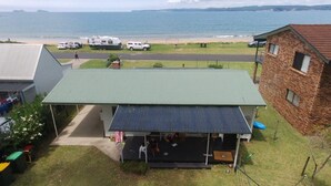 A house with a green roof, a covered porch, and a view of the beach and sea.