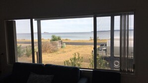 A room with a large window overlooking a beach and a parking area.