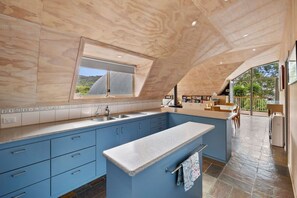 Una cocina moderna con armarios azules, una isla grande y un ventanal con vistas a un jardín.