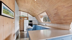 A kitchen with a wooden ceiling, blue cabinets, and a large island.