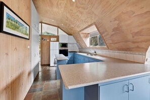 A kitchen with a wooden ceiling, blue cabinets, and a large island.