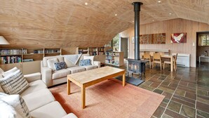 A spacious living area with a high ceiling, a fireplace, and a cozy seating arrangement.