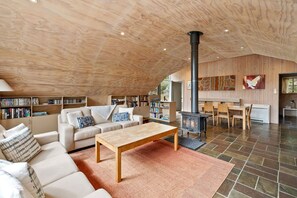 A spacious living area with a high ceiling, a fireplace, and a cozy seating arrangement.