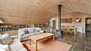 Cozy living area with a high ceiling, wood-burning stove, and comfortable seating.
