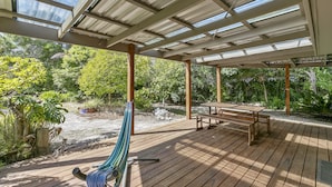 A covered outdoor area with a wooden deck, a hammock, and a table and bench set. - Oceans 12 (Anglesea)