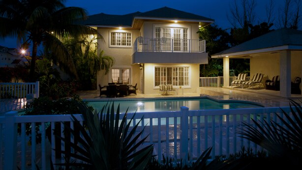A two-story house with a swimming pool, a balcony, and outdoor furniture.
