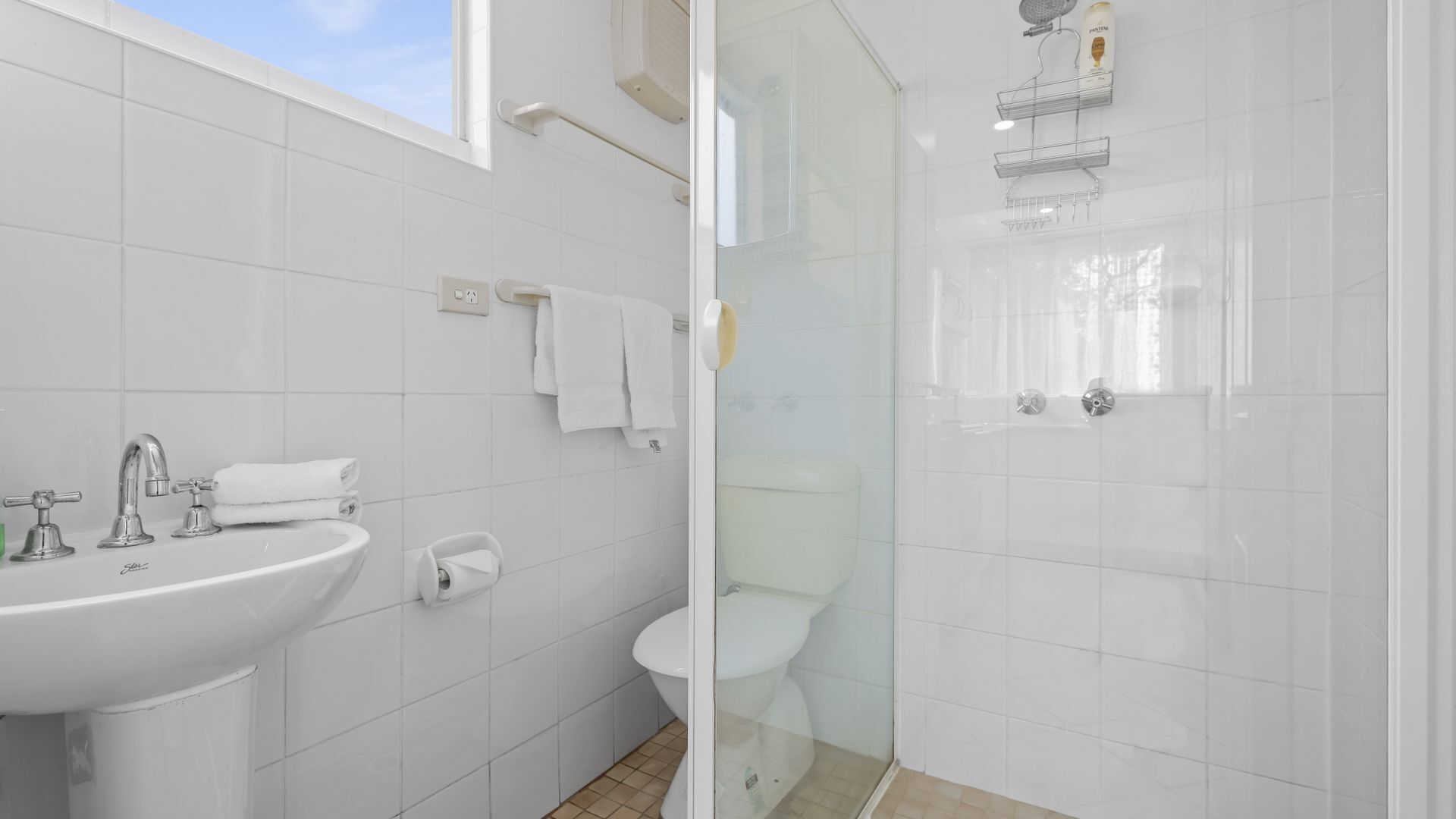 A modern bathroom with a glass-enclosed shower, a white sink, and a toilet.
