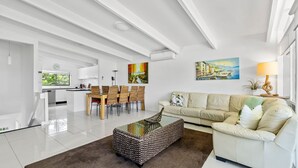 Una sala de estar moderna con sofá, mesa de centro y zona de comedor.