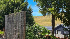 A garden area with a bamboo fence, potted plants, and a view of a house in the background. - Quiet self-contained 3 km from Nelson CBD  (Atawhai)