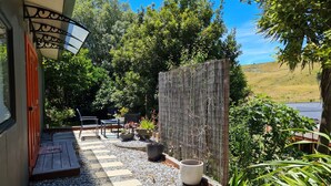 A patio with outdoor furniture, a wooden deck, and a view of a hillside. - Quiet self-contained 3 km from Nelson CBD  (Atawhai)