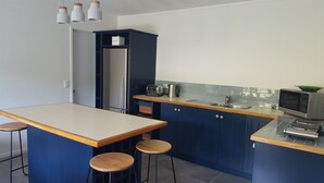A modern kitchen with a central island, bar stools, a microwave, and a toaster. - Quiet self-contained 3 km from Nelson CBD  (Atawhai)