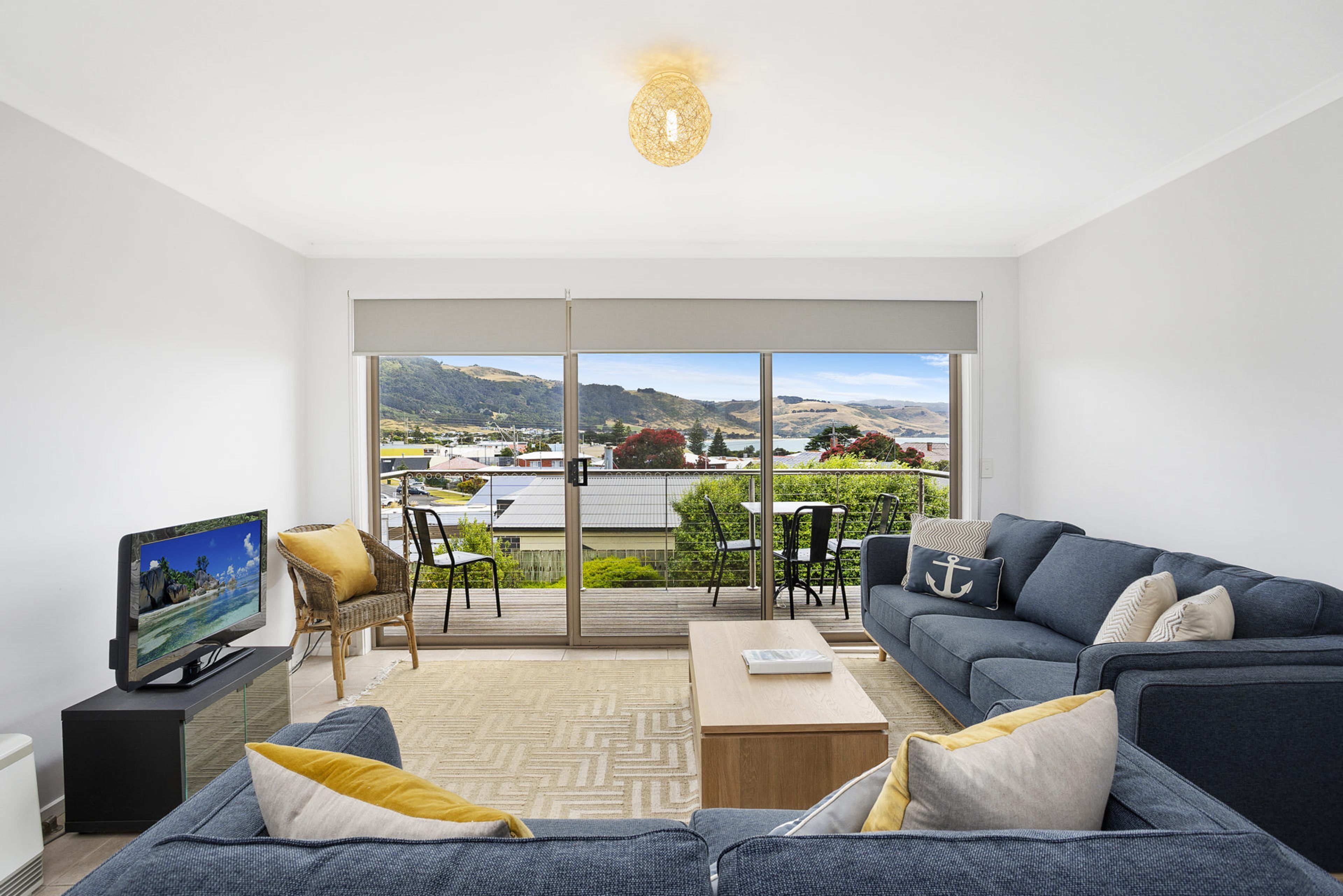 A modern living room with a large sliding glass door leading to an outdoor patio.