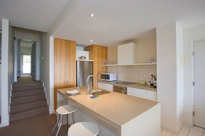 Una cocina moderna con una isla central, electrodomésticos de acero inoxidable y una pared de acento de madera.