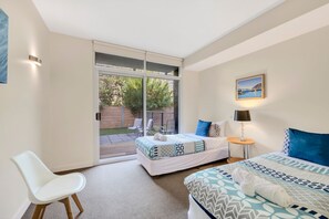 A bedroom with a bed, a chair, a table, and a painting on the wall.