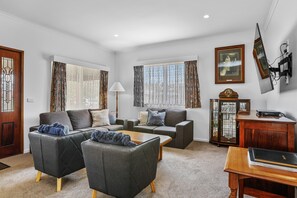 A living room with a sofa set, a coffee table, and a side table with a lamp. - Aunty Wins (Apollo Bay)