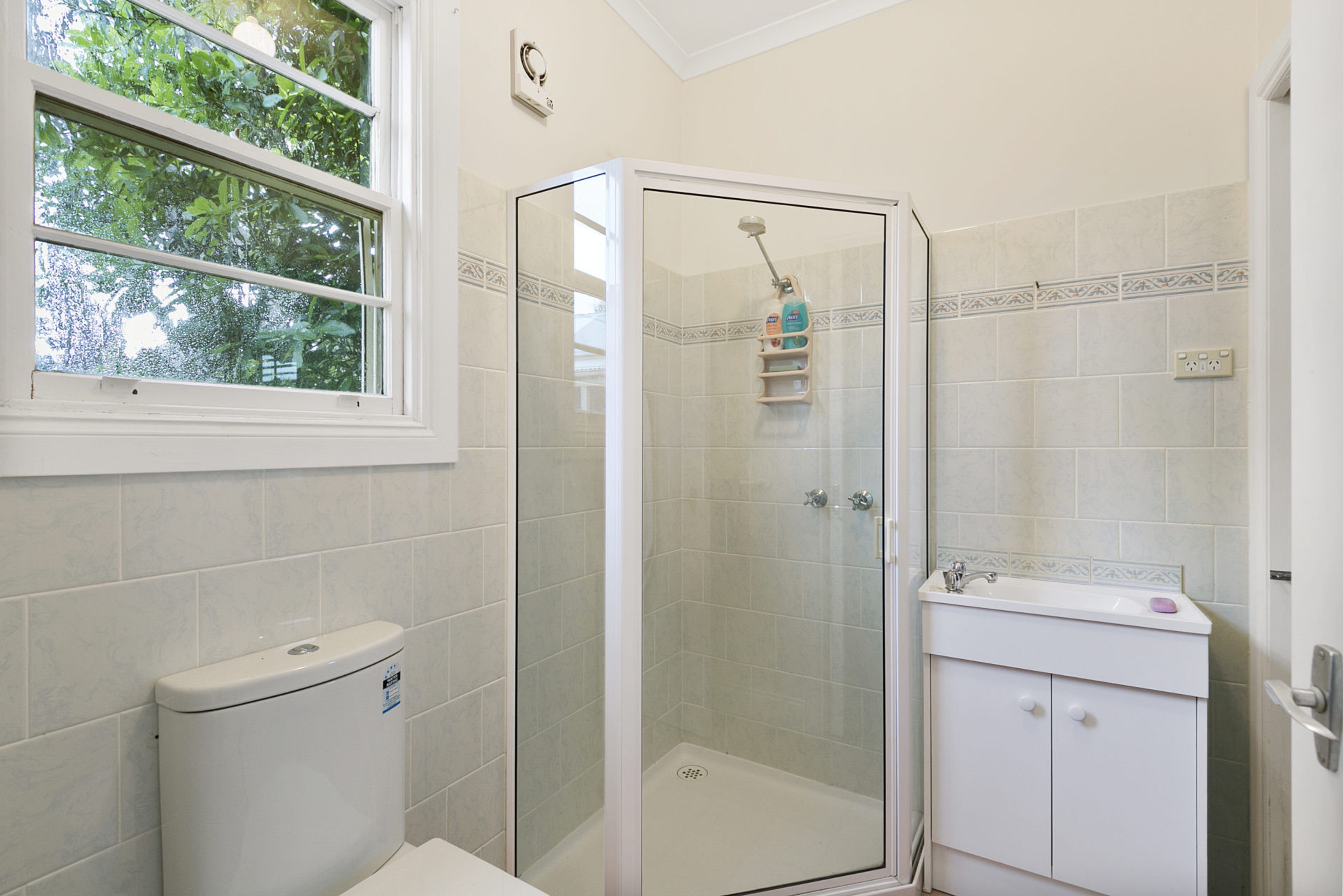 A bathroom with a toilet, a shower enclosure, and a sink.