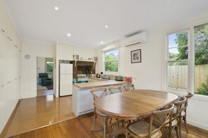 A kitchen with a central island, wooden dining table, and chairs.