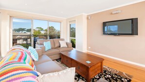 A modern living room with a sofa, coffee table, and a flat-screen TV mounted on the wall.