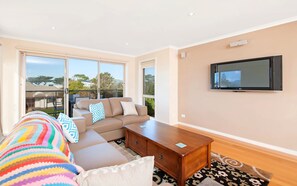 A modern living room with a sofa, coffee table, and a flat-screen TV mounted on the wall.
