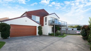 A modern two-story house with a garage, a balcony, and a well-maintained lawn.