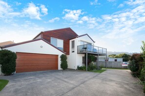 A modern two-story house with a garage, a balcony, and a well-maintained lawn.