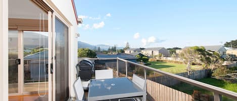 Ein Balkon mit Tisch und Stühlen, der auf einen Wohnbereich mit Häusern und einem klaren Himmel blickt.