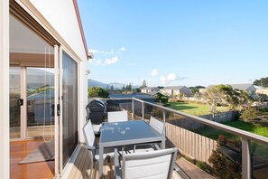 A balcony with a table and chairs, overlooking a residential area with houses and a clear sky.