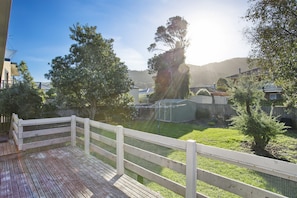 A wooden deck with a white fence, a grassy yard, and houses in the background. - Apollo Bay People N Paws (Apollo Bay)