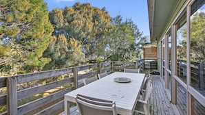 A wooden deck with a table and chairs, overlooking a forested area. - Apollo Bay People N Paws (Apollo Bay)