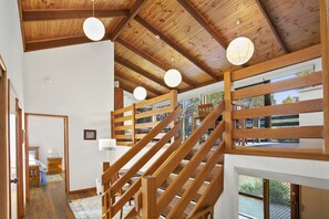 A wooden staircase with a view of the outdoors through large windows. - Apollo Bay People N Paws (Apollo Bay)