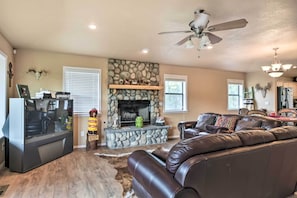 A living room with a stone fireplace, leather sofa, and a television. - Ruidoso Home w/ Deck & Grill, Near Grindstone Lake (Ruidoso)
