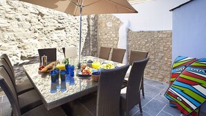 A dining table with wicker chairs, a glass top, and a large umbrella. - High House (6), Tenby , Pembrokeshire (Tenby)