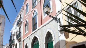 A narrow cobblestone street lined with historic buildings featuring arched windows and green doors. - Arthistorian's Residence ★ central & sunny (Lisboa)