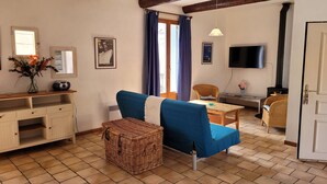 Un soggiorno accogliente con un divano blu, mobili in vimini, una TV e un camino.