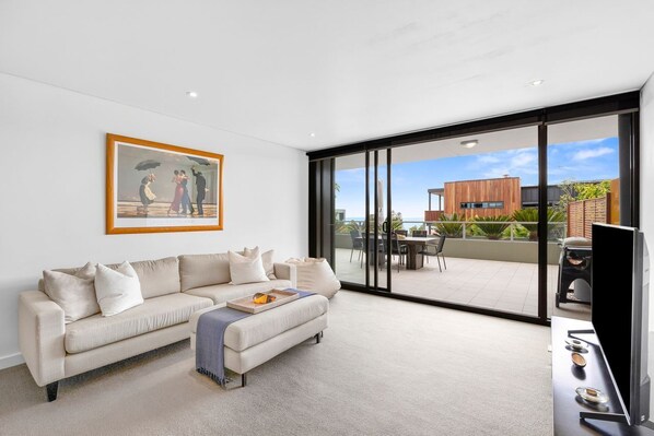 A modern living room with a sofa, a coffee table, and a painting on the wall. - Lorne Chalet Apartment 36 (Lorne)